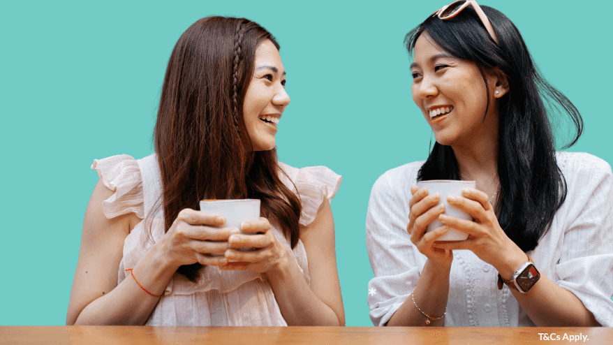 Two female students holding coffee cups against a turquoise background with UniLodge Park Avenue branding and referral promotion.