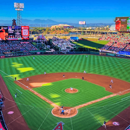 Wide-angle view of Angel Stadium baseball field during a game with crowds in the stands and mountains in the background