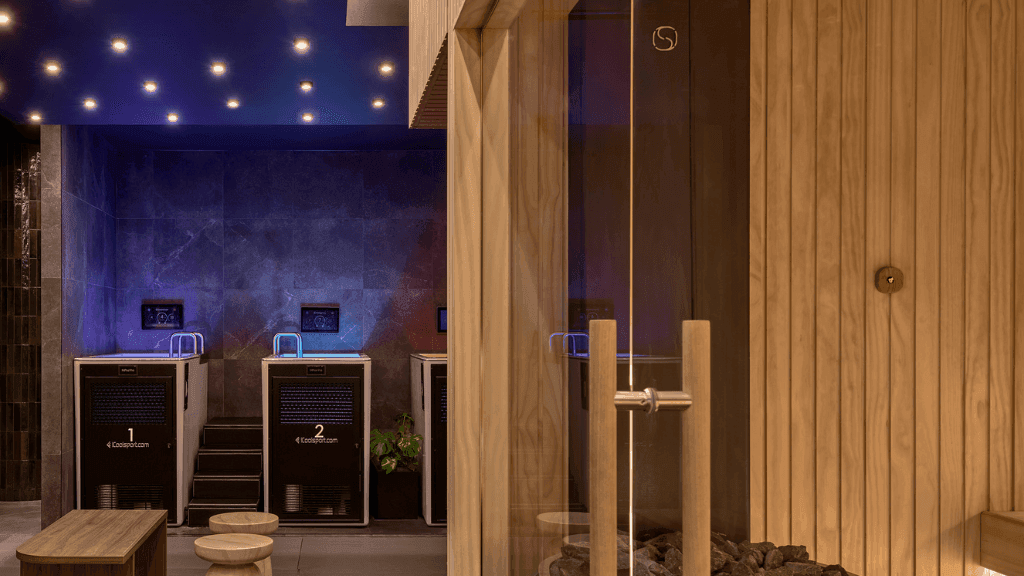 Woman in a dress stands on a balcony overlooking a building from a hotel room.