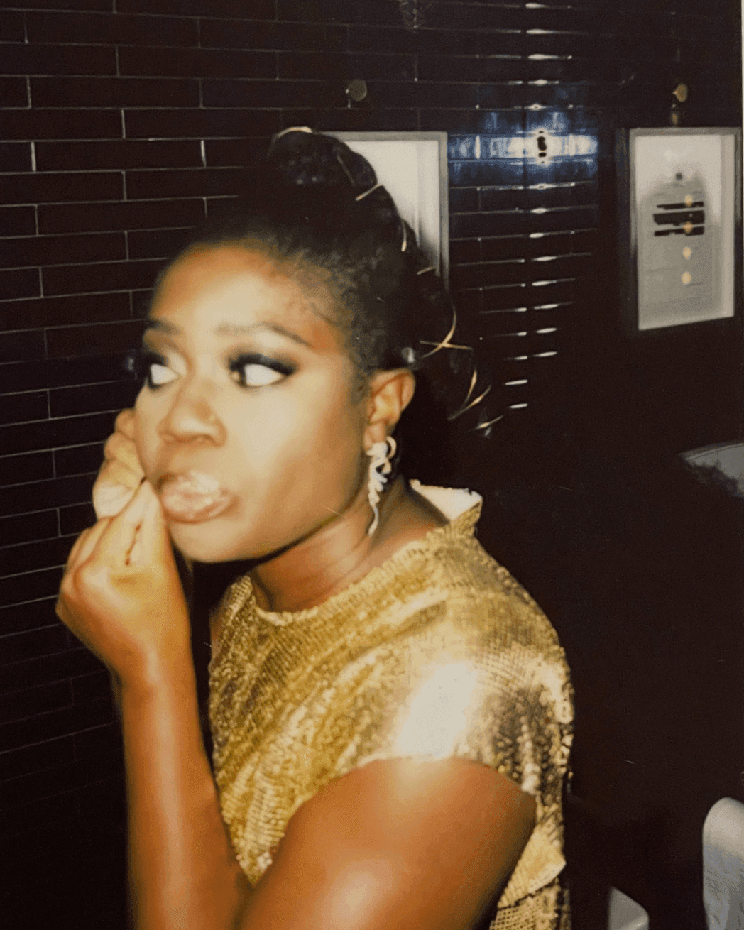 Woman in a stunning golden dress fixing her earring, likely at an event at The Londoner