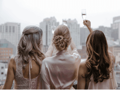 Three women in elegant robes toast with champagne glasses at Warwick Le Crystal
