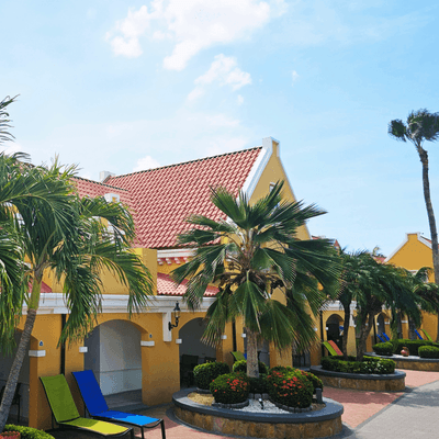 Exterior of Amsterdam Manor Beach Resort with numerous palm trees, and colorful lounge seating areas