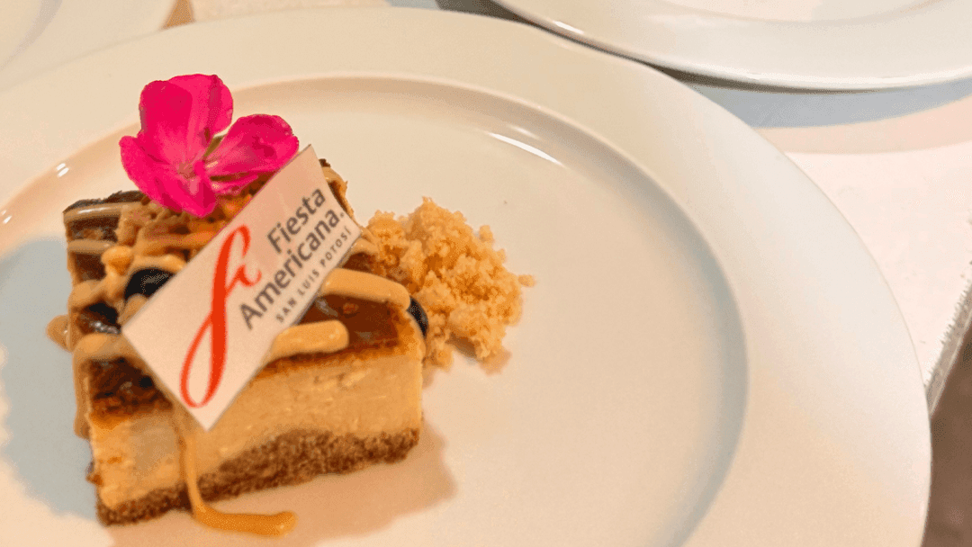 Elegant dessert plates with slices topped with crumbly bits, blueberries, and pink flowers at Fiesta Americana Travelty