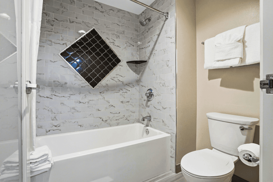 A clean bathroom with a bathtub, toilet, and tiled shower area.