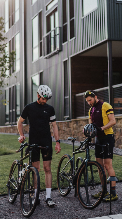 Two bikers checking out their bikes at a station before starting their ride