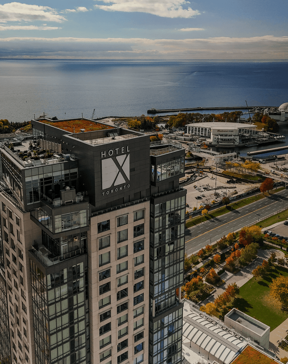 Aerial view of Hotel X Toronto, with rooftop pool and terraces perched above Lake Ontario, near Budweiser Stage waterfront