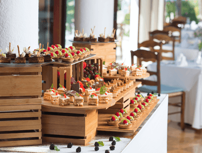 Assorted gourmet desserts displayed on wooden tiers at buffet in Frutas y Flores Restaurant at Buenaventura Grand Hotel and Spa