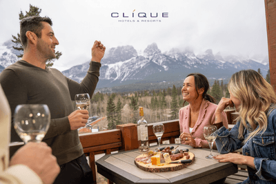 Group of four toasts with wine on a balcony, enjoying a cheese board and a stunning mountain view at Falcon Crest Lodge