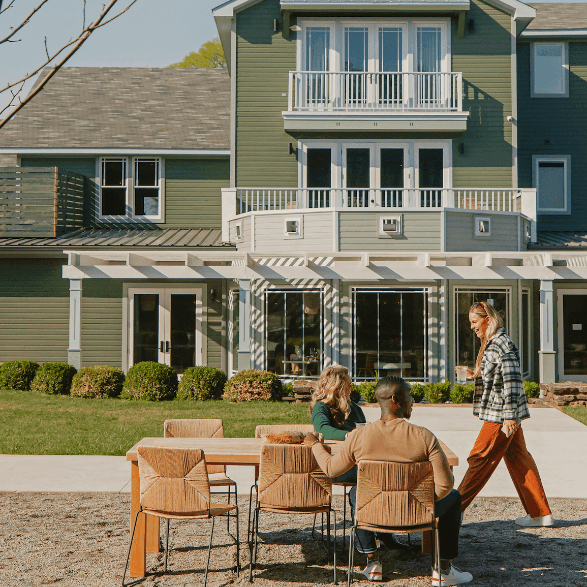 People seated at a table and walking in front of the green colored Stonebreaker hotel..