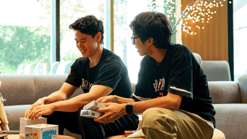 Two men playing a board game together on a couch.