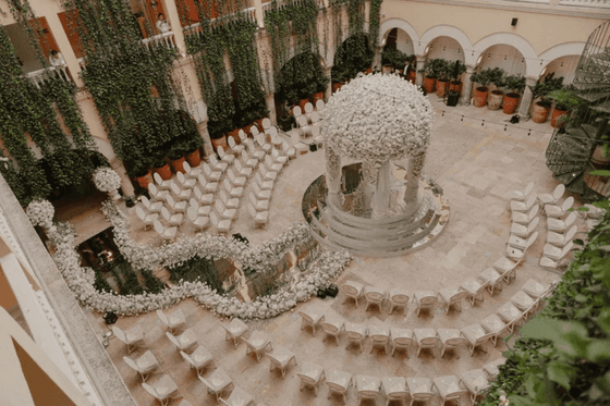 Patio colonial decorado con flores blancas y sillas dispuestas para ceremonia en Hotel Charleston Santa Teresa