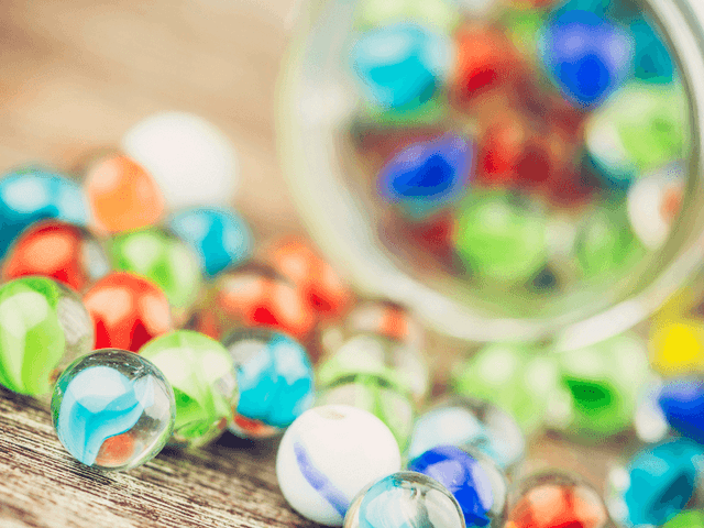 Close-up of colorful glass marbles scattered on a wooden surface featuring event at El Conquistador Resort