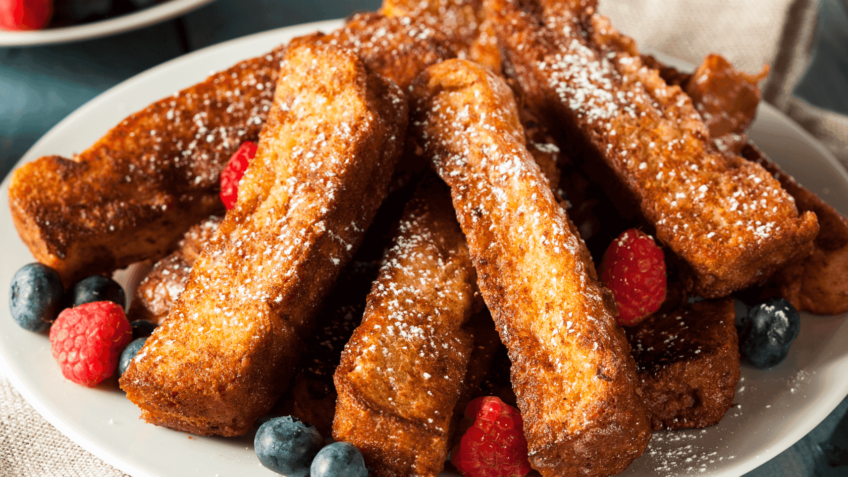 A plate of french toast stacked high on an assortment of fresh berries