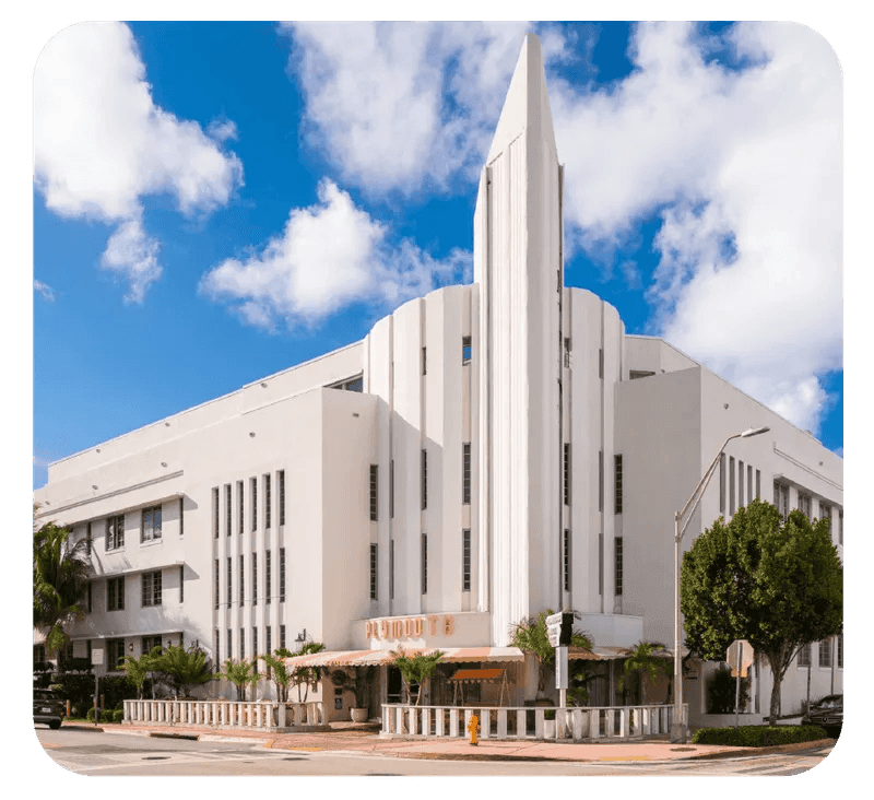 A white building with a pointed tower under a blue sky with clouds.