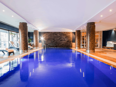 Indoor swimming pool with loungers at Amora Hotel