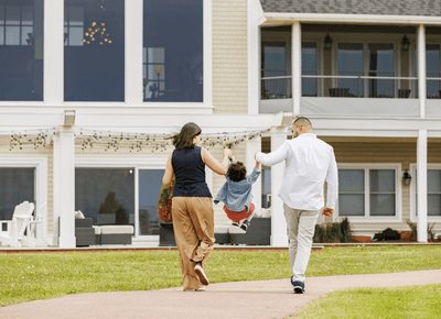 Parents swinging their young child while walking on a path by green lawns outside Rodd Crowbush Golf & Beach Resort