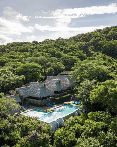 Piscina al aire libre rodeada de villas con techo de paja en Morgan's Rock Reserve & Ecolodge, uno de los hoteles de San Juan del Sur.