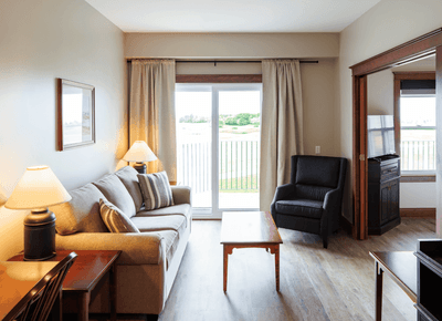 White king bed, wooden headboard, and golf course views in Accessible King Suite View at Rodd Crowbush Golf & Beach Resort