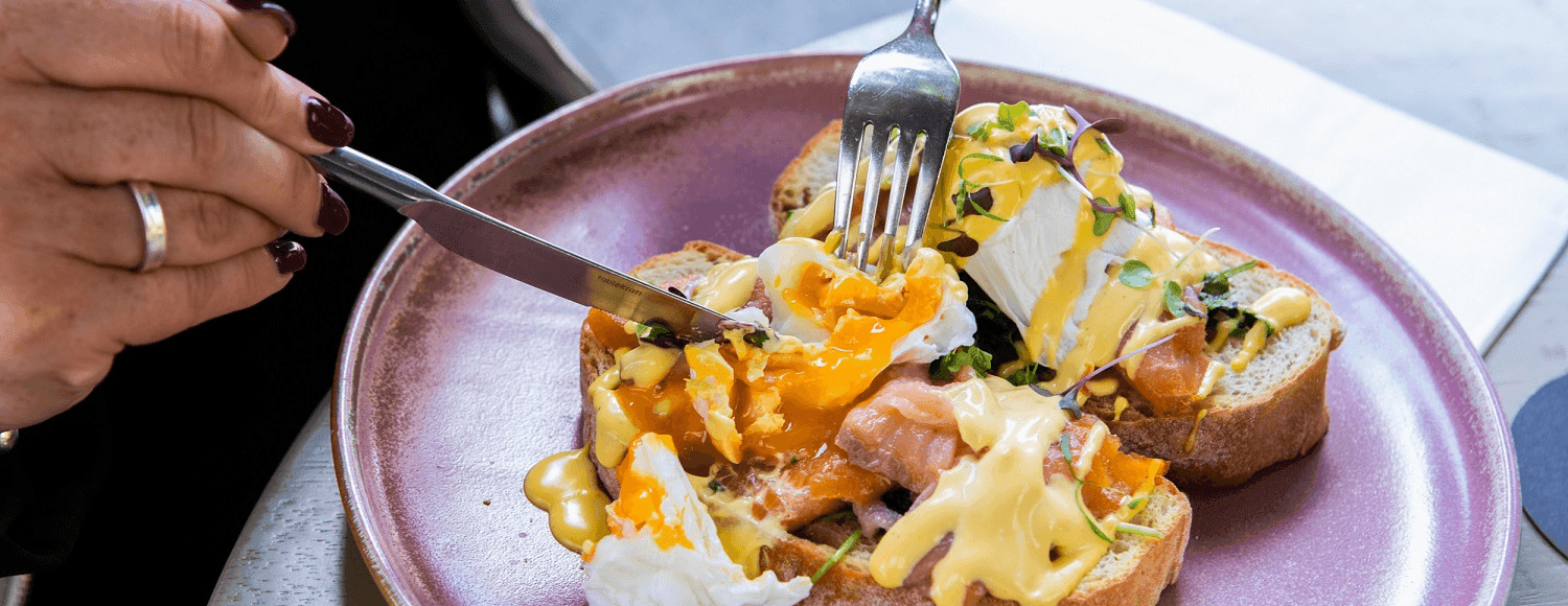 Close-up of person enjoying a porched egg toast at Pullman King George Square