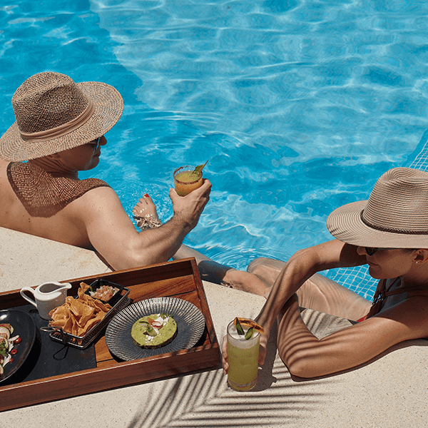Pareja disfrutando una comida gourmet junto a la alberca mientras toma el sol en Villa Premiere Boutique Hotel & Romantic Getaway en Puerto Vallarta
