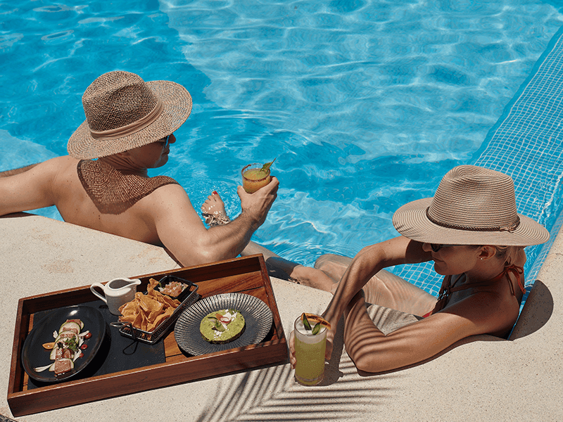 Pareja disfrutando una comida gourmet junto a la alberca mientras toma el sol en Villa Premiere Boutique Hotel & Romantic Getaway en Puerto Vallarta