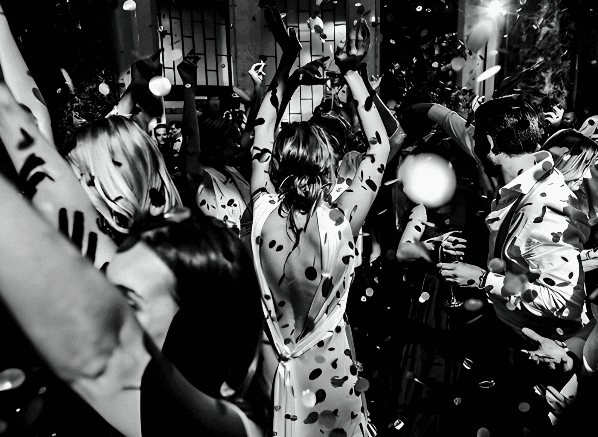 Black and white image of a crowd dancing and celebrating with confetti.