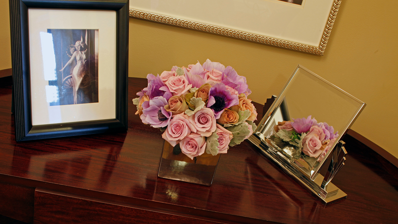 Photo frame, flower vase, and mirror on a table in Hollywood Suite at Warwick New York