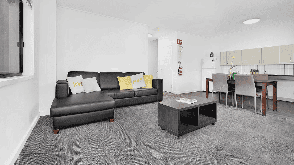 Modern open-plan living area with gray sectional sofa, dining table, and kitchen at Springfield Central