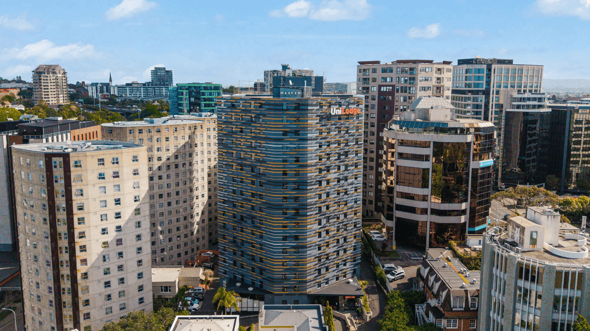 A modern urban skyline featuring UniLodge Auckland City among other buildings.