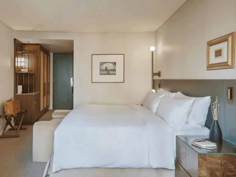 Clean hotel bedroom with white bedding, artwork, and neutral color palette