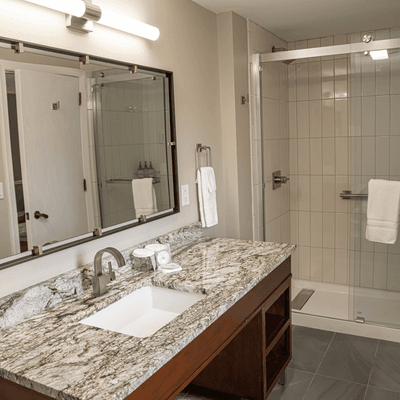 Spacious bathroom vanity with marble countertop facing a glass walk-in shower at La Tourelle Hotel and Spa