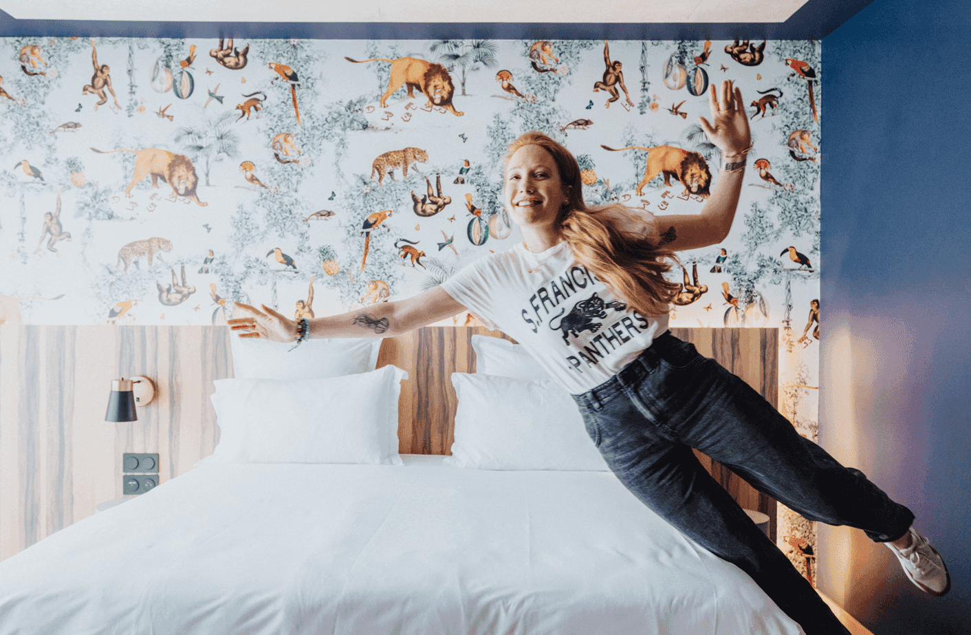 Woman jumping to the bed in Cosmik Room at Kopster Hotel Paris Ouest Colombes