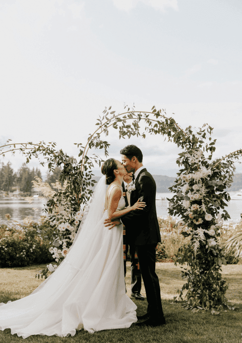 Couple kissing by the flower arch in the wedding ceremony at Alderbrook Resort & Spa