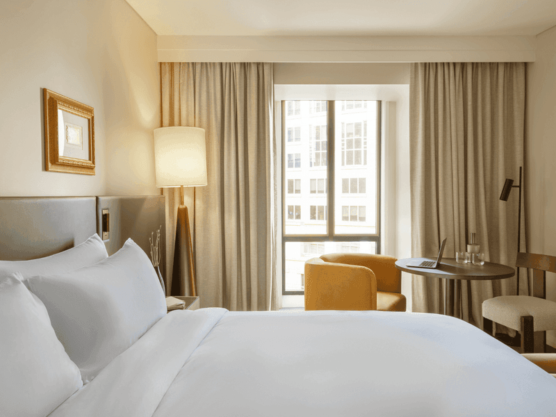 Hotel suite with king bed, seating area, large windows and contemporary furnishings