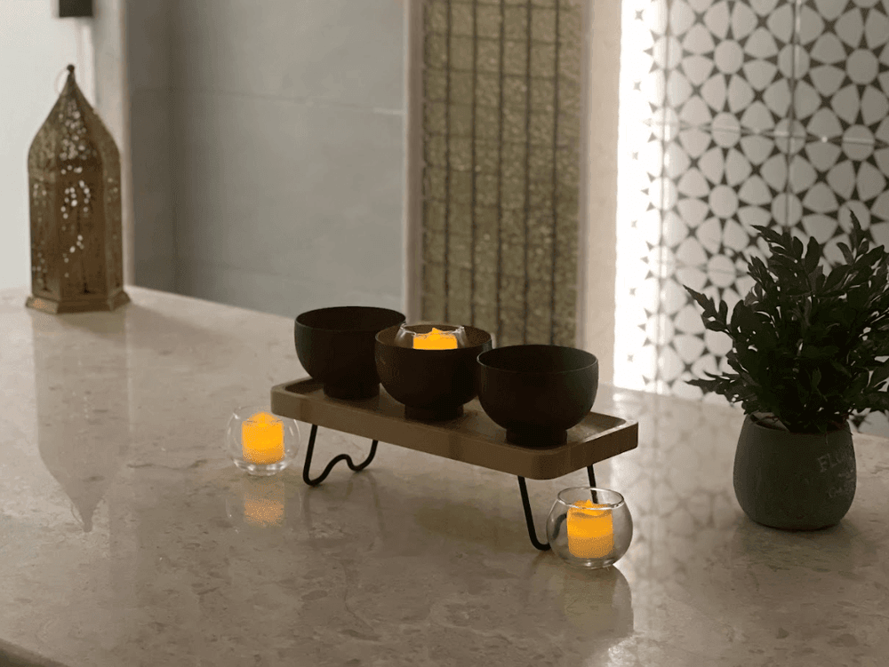 Candle bowls on a tray by a plant on a marble counter, spa near a gold lantern at Warwick Al Jubail