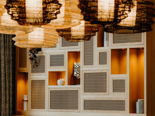 A wall with shelves and chandeliers in CineScope Restaurant at Paramount Hotel Midtown