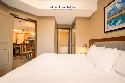 Comfortable suite at Falcon Crest Lodge features a king-size bed and an open doorway revealing a kitchen and dining area