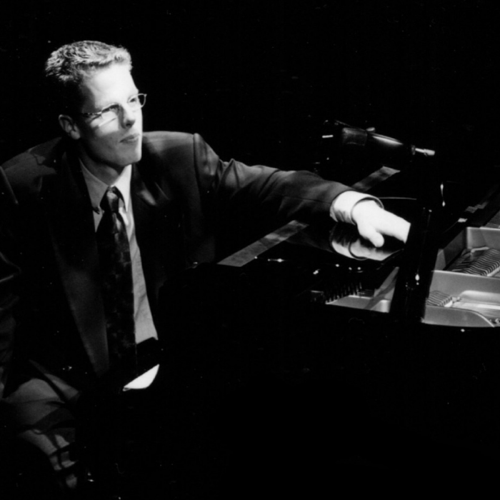 Piano Player, Darin Macdonald, in suit sitting at piano black and white photo