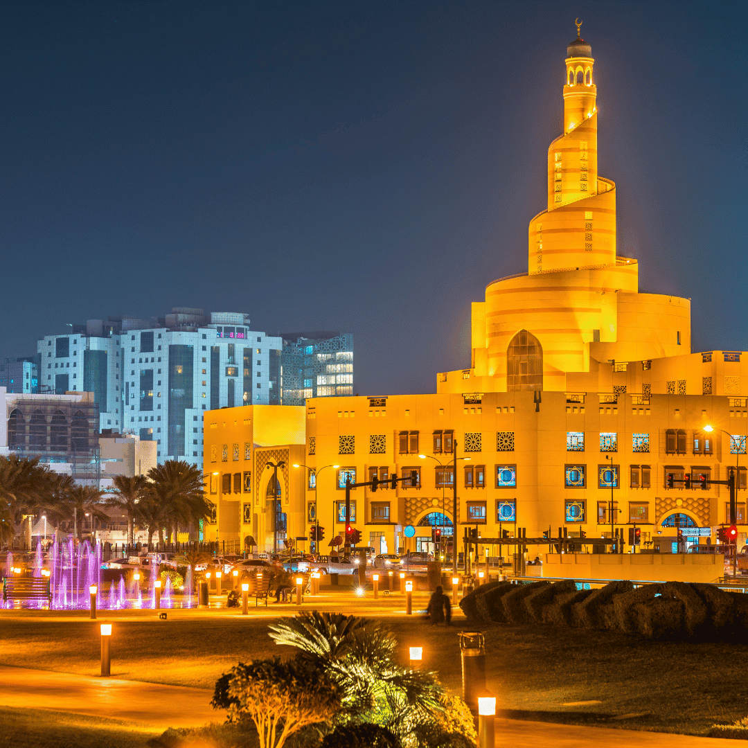 Illuminated Souq Waqif with a prominent central tower at night in an urban setting.