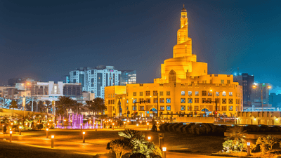 Illuminated Souq Waqif with a prominent central tower at night in an urban setting