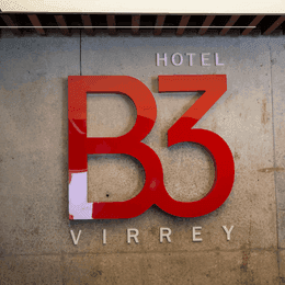 Large sign mounted directly onto a textured grey concrete facade by the entrance at Hotel B3 Virrey