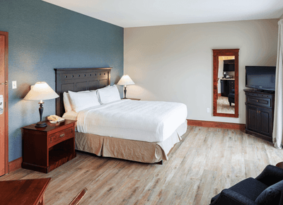Accessible King View with white bed, blue accent wall, TV, and wooden furnishings at Rodd Crowbush Golf & Beach Resort