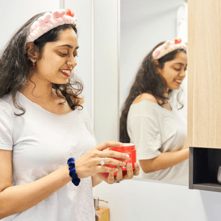 Smiling woman holding a cup in front of mirror at UniLodge Lincoln House.