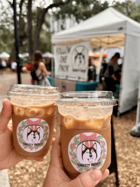 Two hands holding iced coffee at an Orlando farmers market near Rosen Inn.