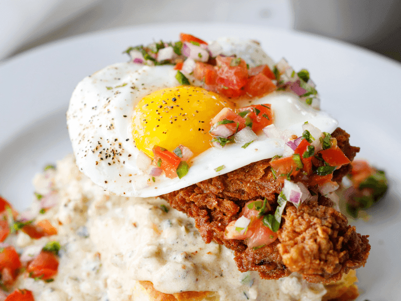 A plate of food with fried chicken, a fried egg, and grits.
