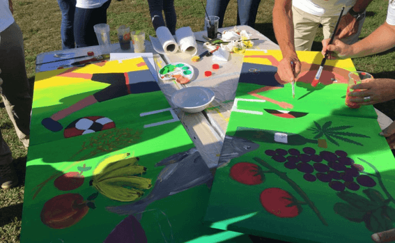 People painting colorful images on a large canvas outdoors at Starling Hotels in Lausanne Switzerland