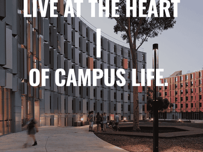Modern apartment buildings with students gathering in a central courtyard featuring mature trees at dusk.