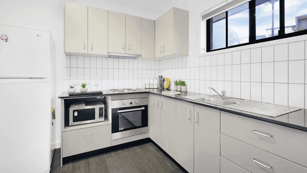 Modern kitchen with white cabinetry, stainless steel appliances, and white tile backsplash at Springfield Central