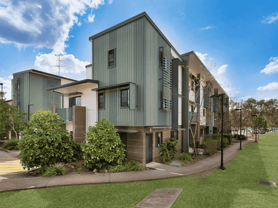 Modern multi-story residential buildings with green and beige facades surrounded by landscaped lawns and pathways in Springfield Central.