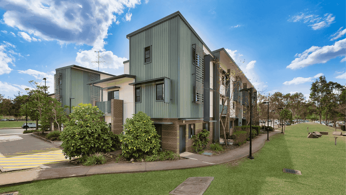 Modern multi-story residential buildings with green and beige facades surrounded by landscaped lawns and pathways in Springfield Central.